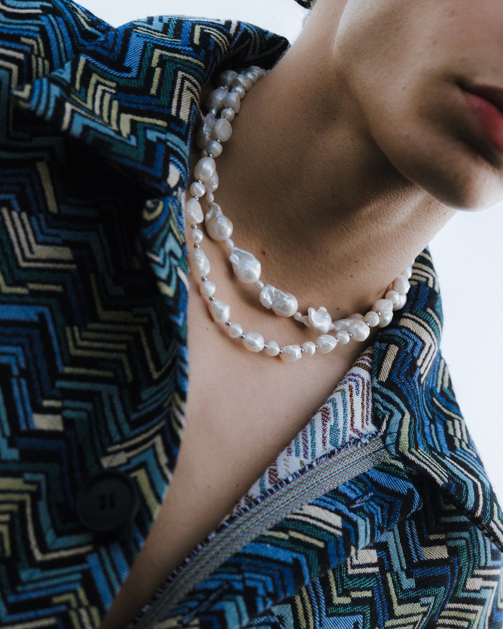 Süßwasserperlenkette getragen am Hals eines Mannes.